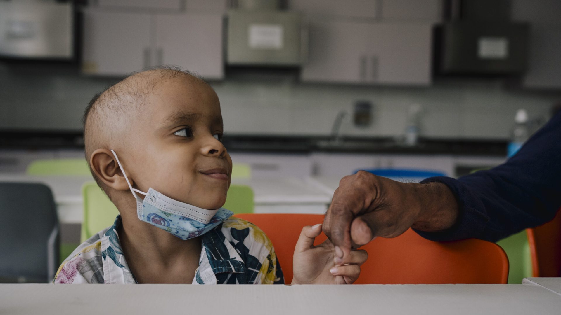 Child hold a hand and smiling up to the person