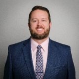 Chris Buesing, President Elect: Listed with his title as Director of Workers Compensation & Workforce Safety at Stormont Vail Health in Topeka, KS. His home address is also in Topeka. His board term is noted as 2024–2026. A professional headshot to the right shows a smiling man with a light beard wearing a grey suit jacket and tie.